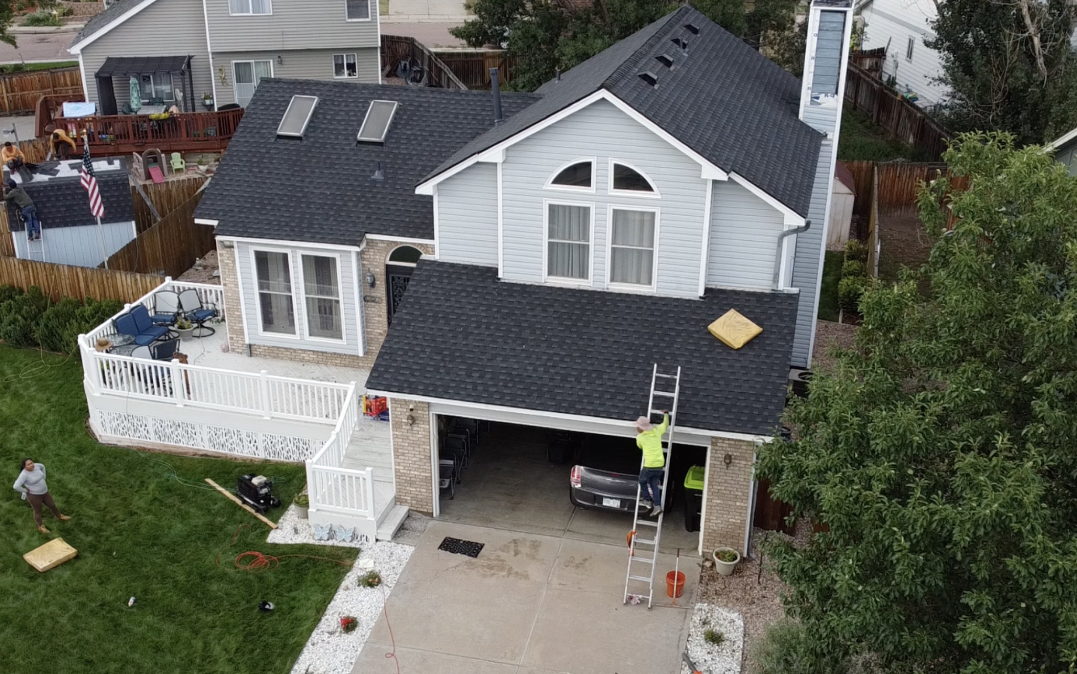 Completed home exterior with new dark roof, siding, windows, and gutters