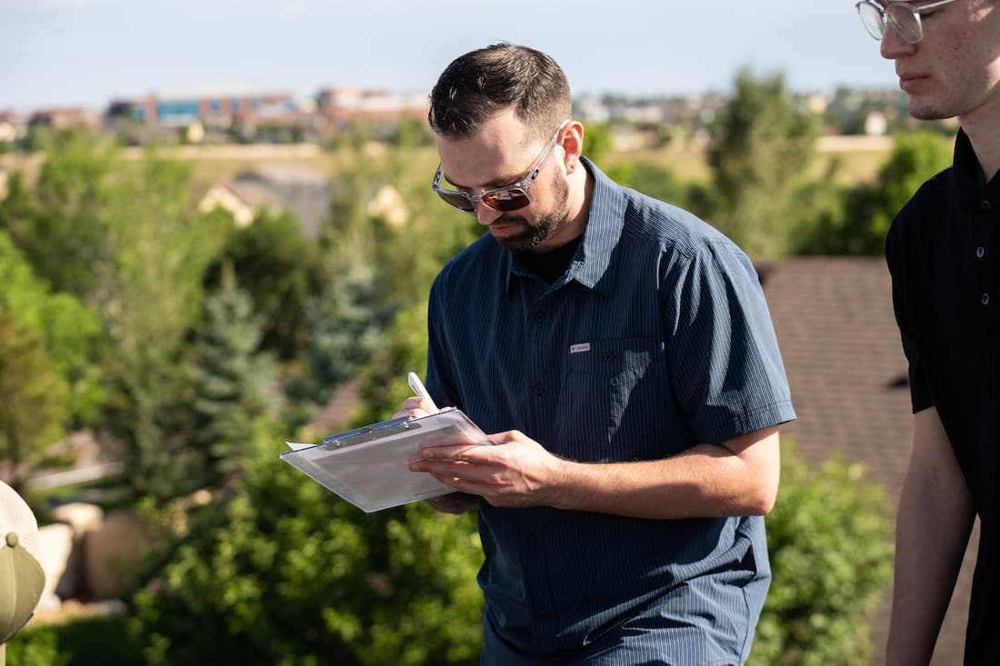 Insurance adjuster on roof reviewing claim